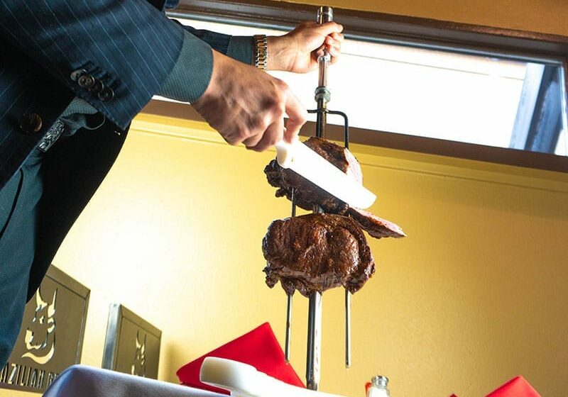 Gaucho carving meat at the table at Boiada Brazilian Grill