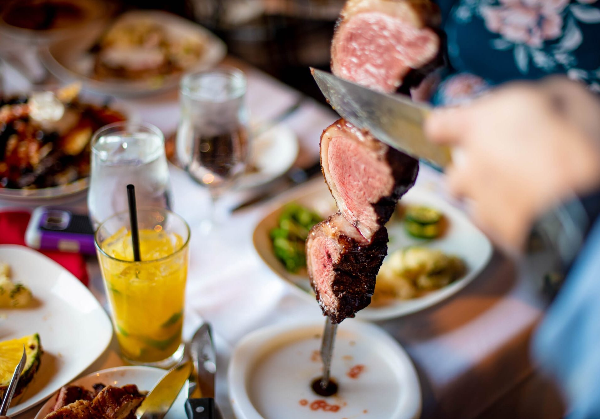 table-of-food cutting meat off a skewer onto a plate
